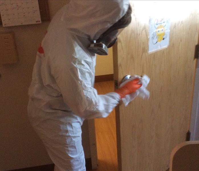 Man wearing PPE Cleaning a door