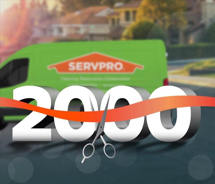 Ribbon being cut in front of the number 2000 with a SERVPRO van in the background