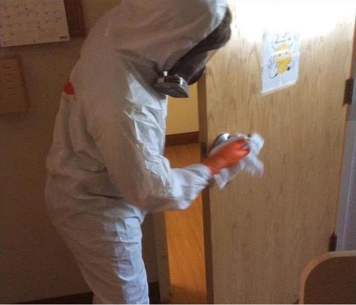A door being cleaned by a man wearing personal protective equipment